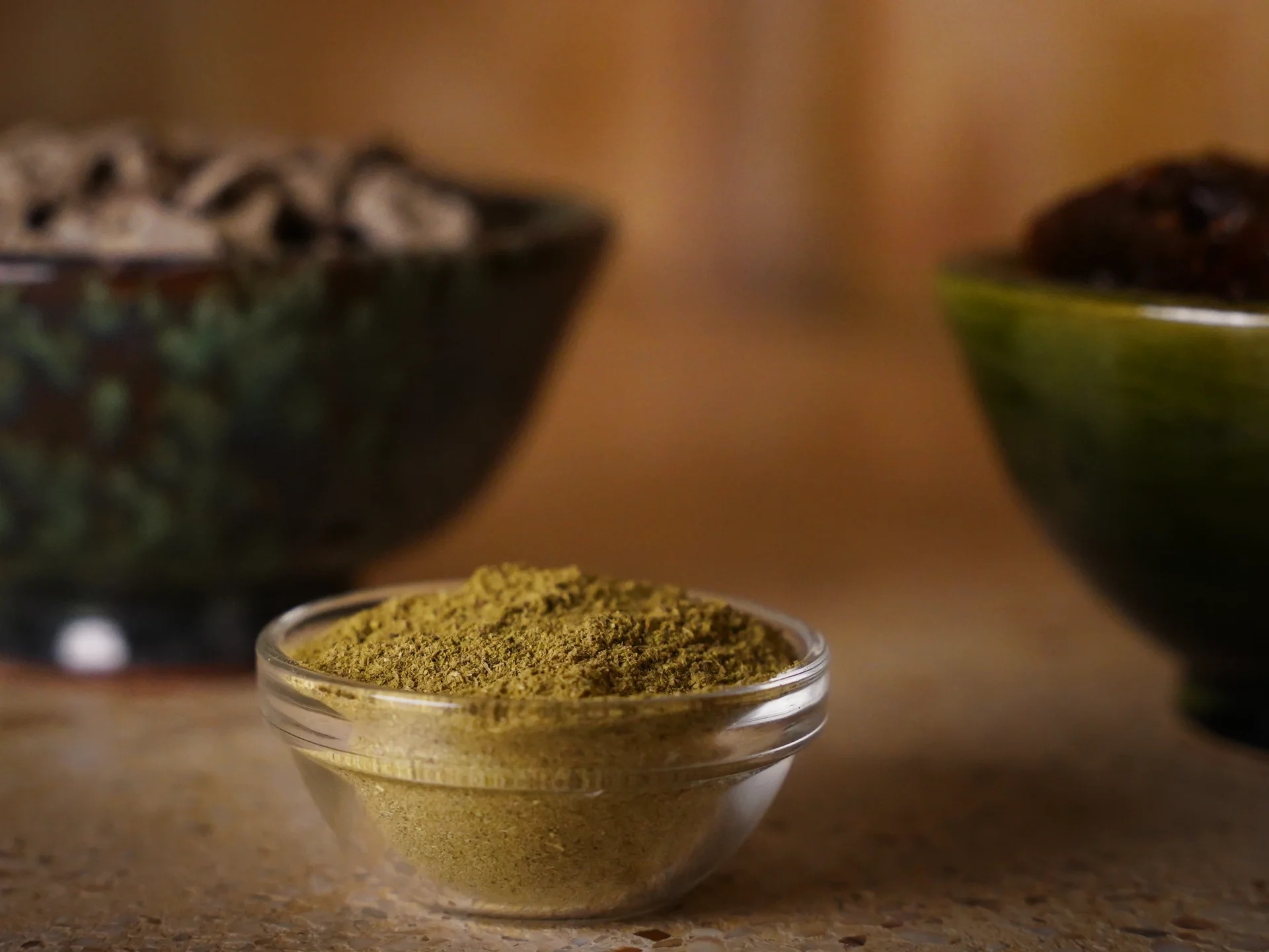 Cuenco de cristal con un producto de hammam en polvo entre cuencos de cerámica