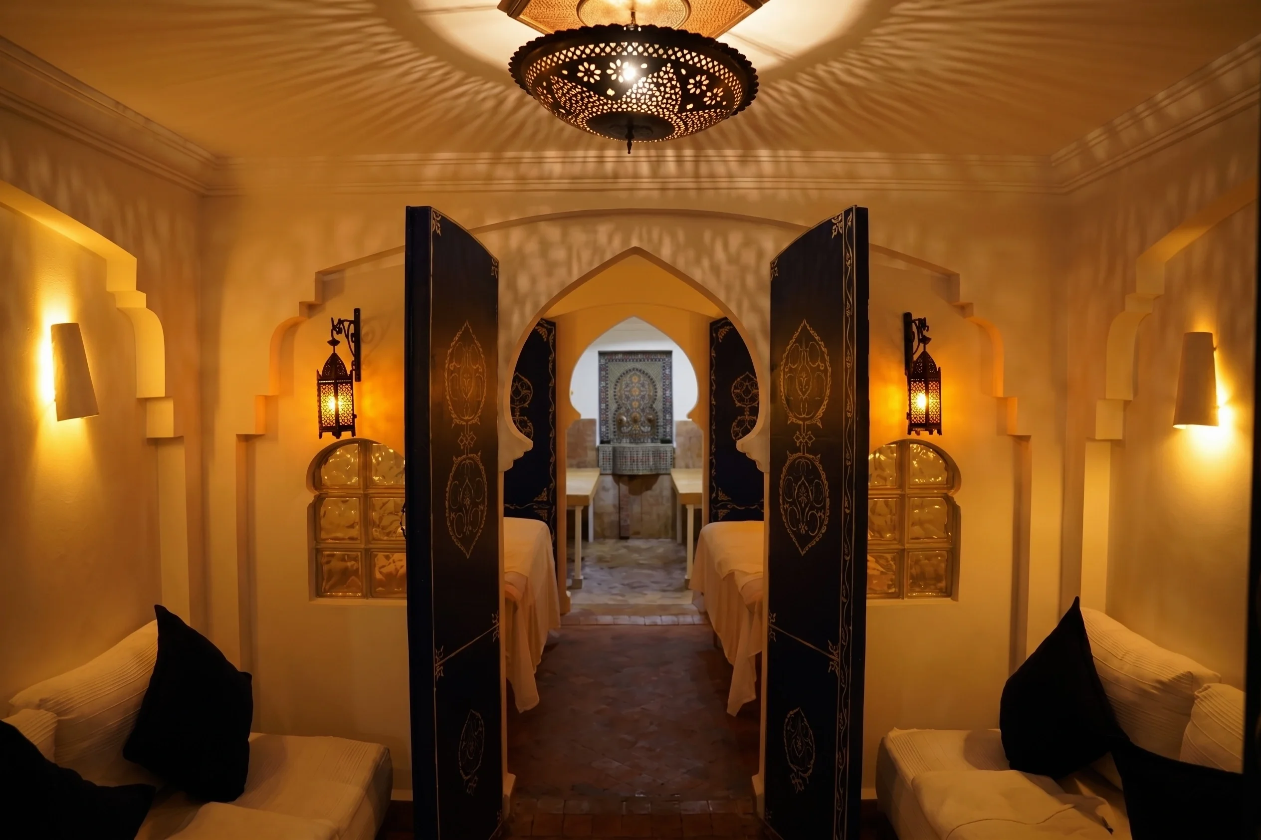 Sala de hammam con arcos, puertas abiertas y camillas de masaje