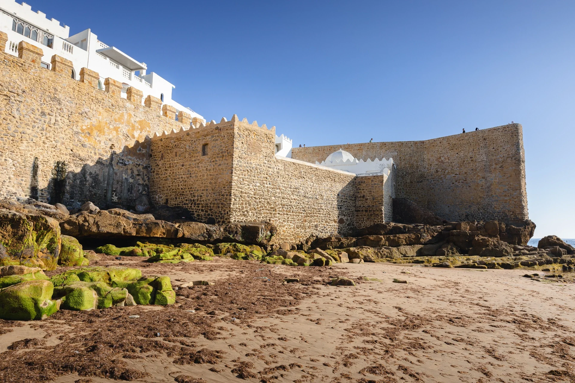 Stone walls of Asilah by the beach at low tide