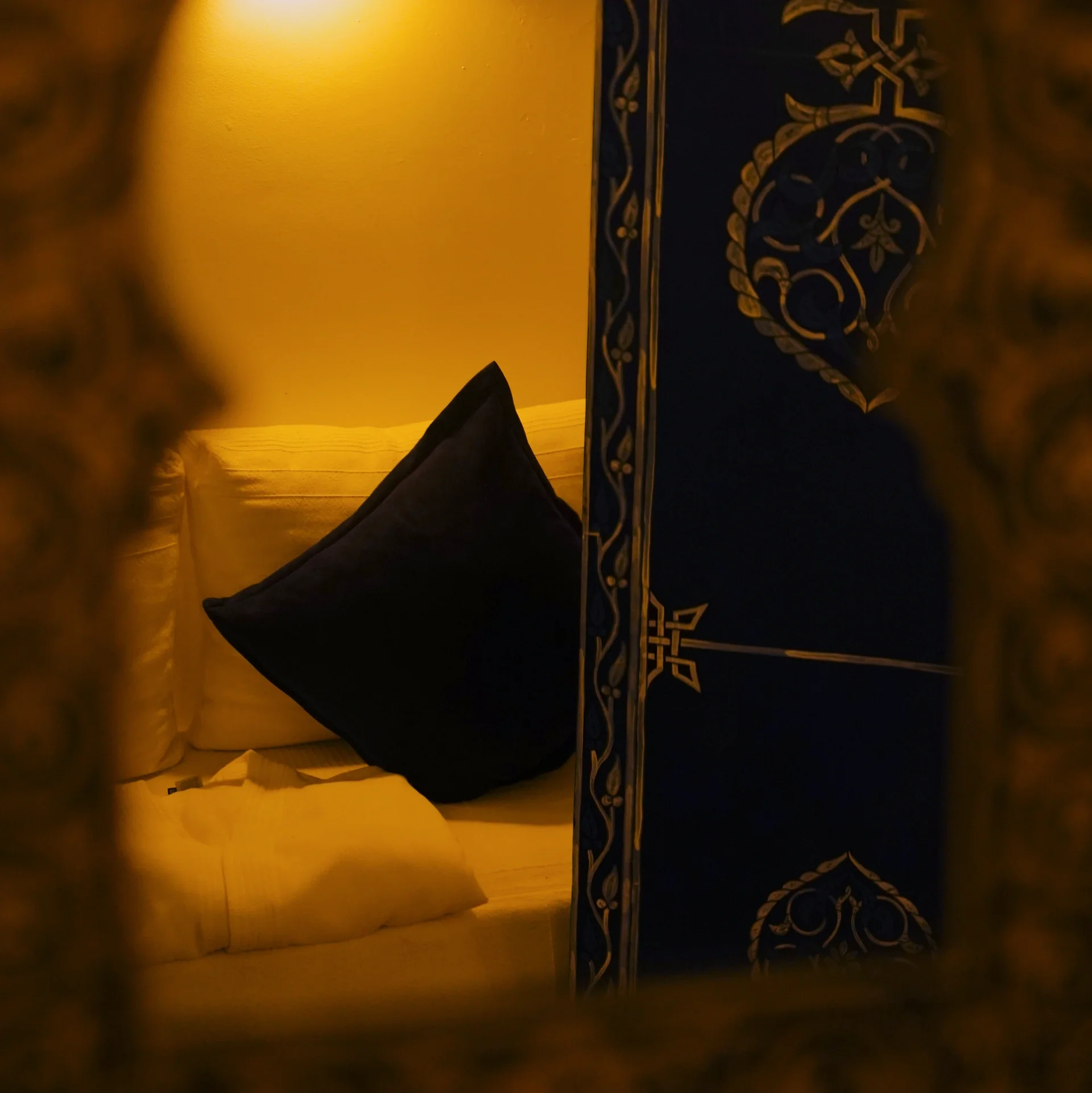 Cojín azul oscuro visto a través de un arco, junto a una puerta decorada